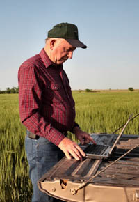 Man typing on laptop in field