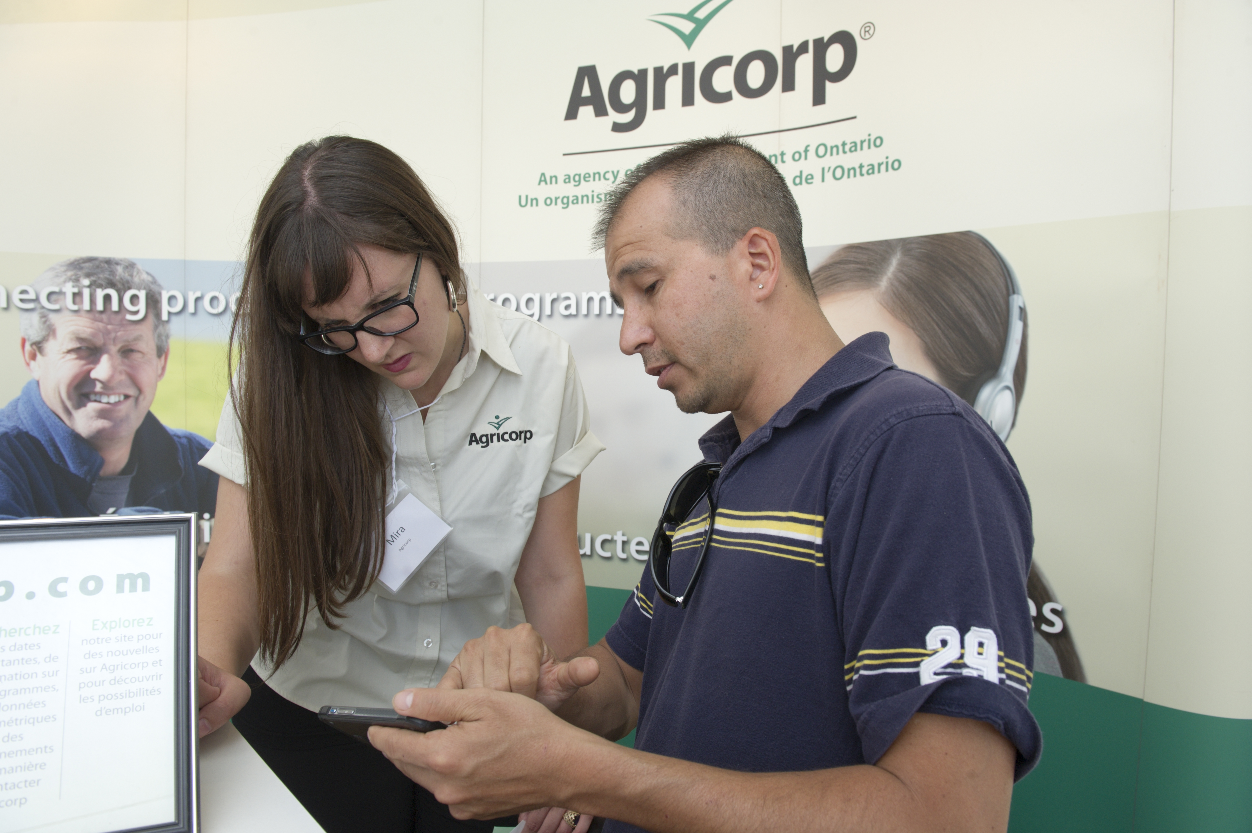 A producer shows an Agricorp staff member something on his phone at a farm show.